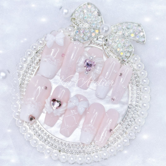 Kawaii Japanese ryousangata jirai style handmade press-on nail set featuring baby pink and white gels, lace french tips, adorned in ribbons, bows, angel wings, hearts, and glitter