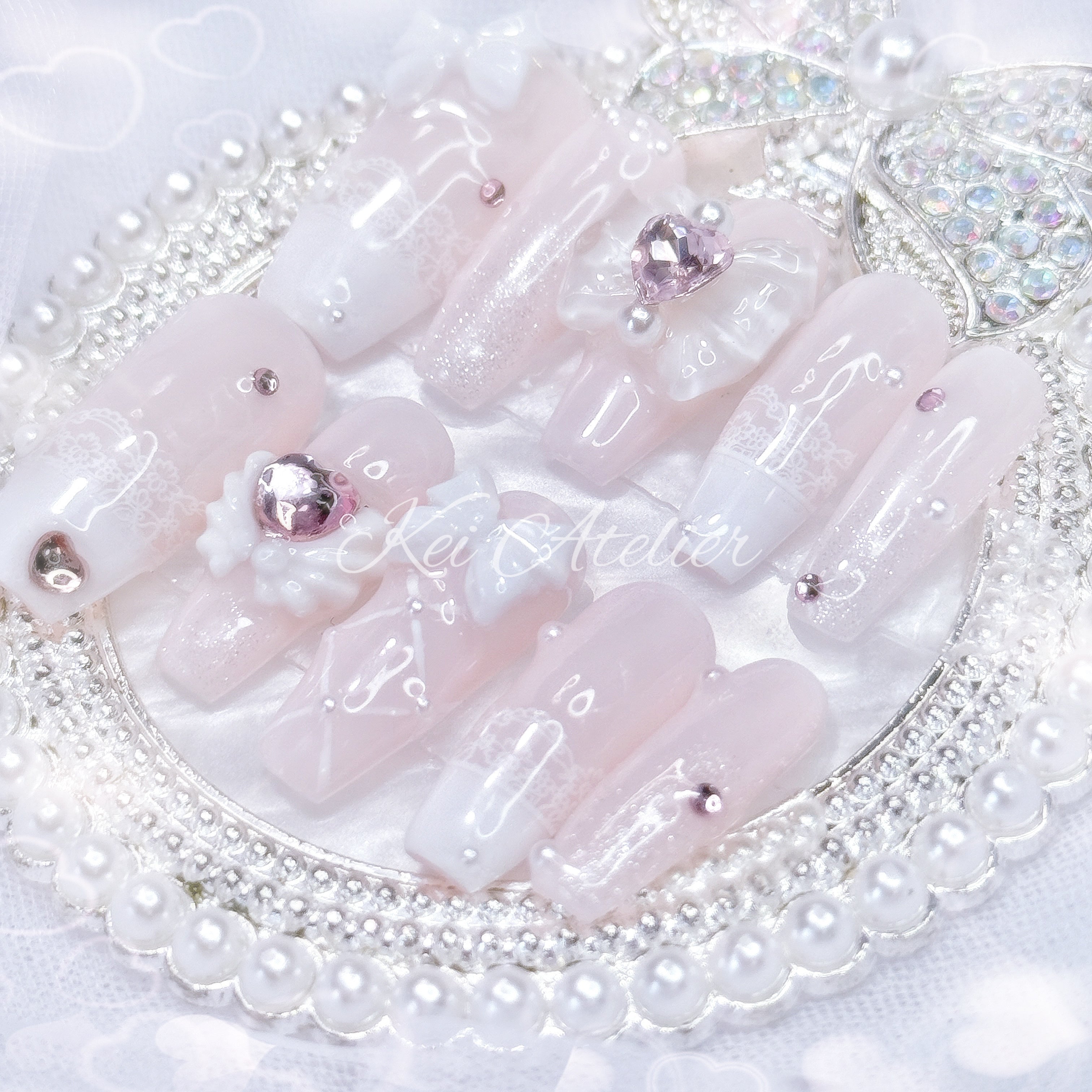 Kawaii Japanese ryousangata jirai style handmade press-on nail set featuring baby pink and white gels, lace french tips, adorned in ribbons, bows, angel wings, hearts, and glitter