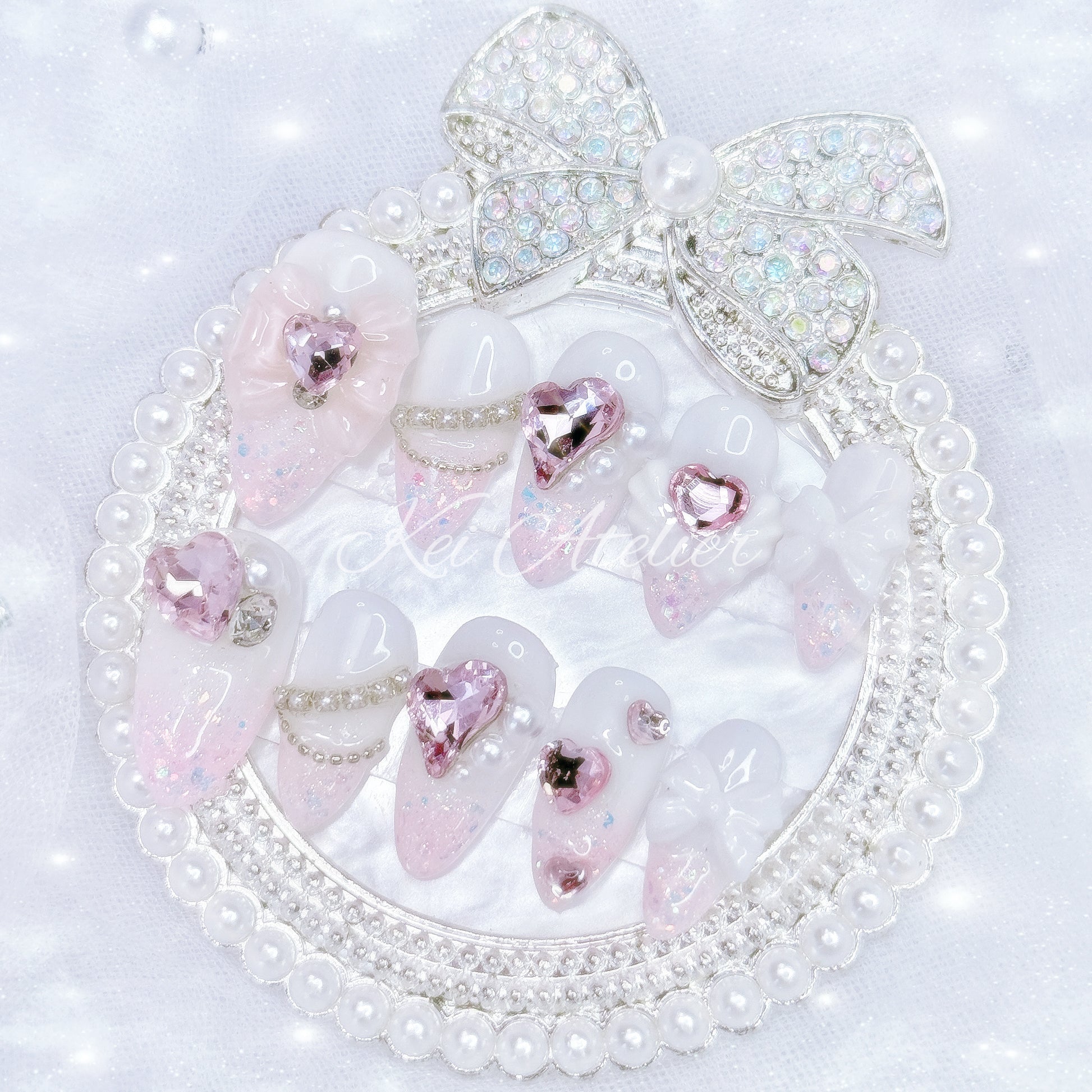 Kawaii Japanese ryousangata jirai style handmade press-on nail set featuring white gel and pink glitter, pink heart rhinestone jewels, angel wings, bows, ribbons, and pearls, inspired by a cupid