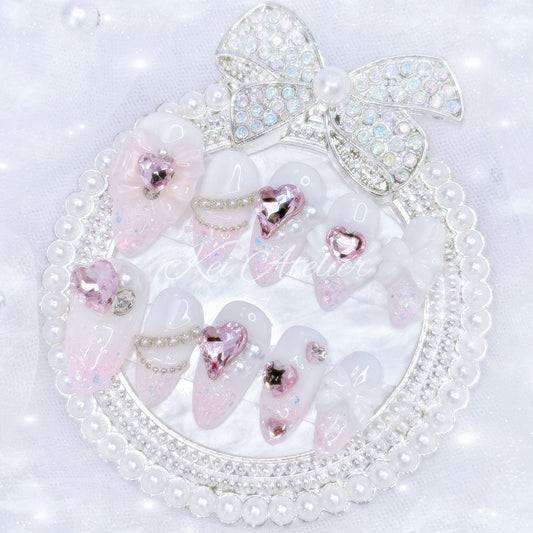 Kawaii Japanese ryousangata jirai style handmade press-on nail set featuring white gel and pink glitter, pink heart rhinestone jewels, angel wings, bows, ribbons, and pearls, inspired by a cupid