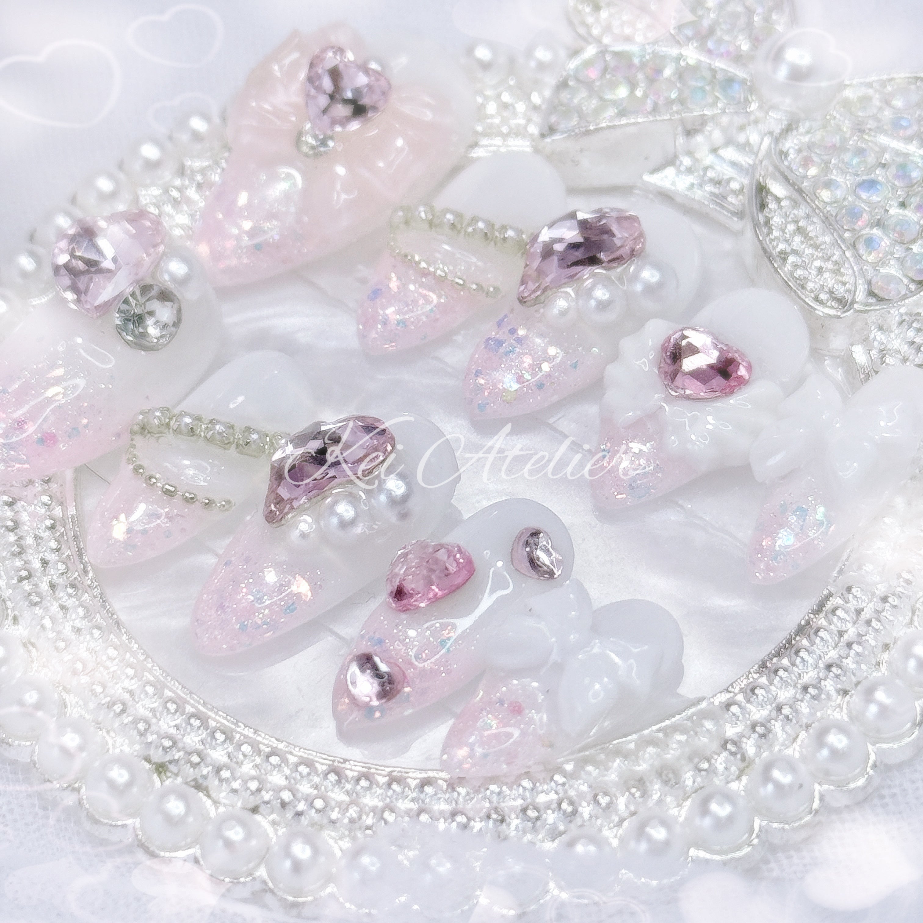Kawaii Japanese ryousangata jirai style handmade press-on nail set featuring white gel and pink glitter, pink heart rhinestone jewels, angel wings, bows, ribbons, and pearls, inspired by a cupid
