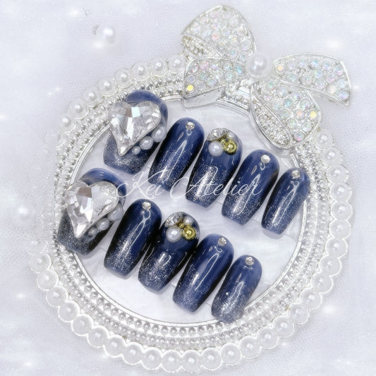 kawaii elegant japanese ryousangata jirai style handmade press-on nail set featuring dark blue and shimmery glitter gels, decorated with pearls, gold caviar beads, rhinestones, jewels, and a big white heart jewel