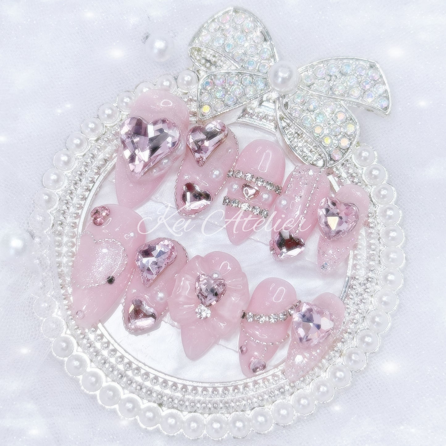 Kawaii Japanese ryousangata jirai style handmade press-on nail set featuring pink sparkly gel, bejeweled in heart crystal rhinestones, pearls, and glitter.