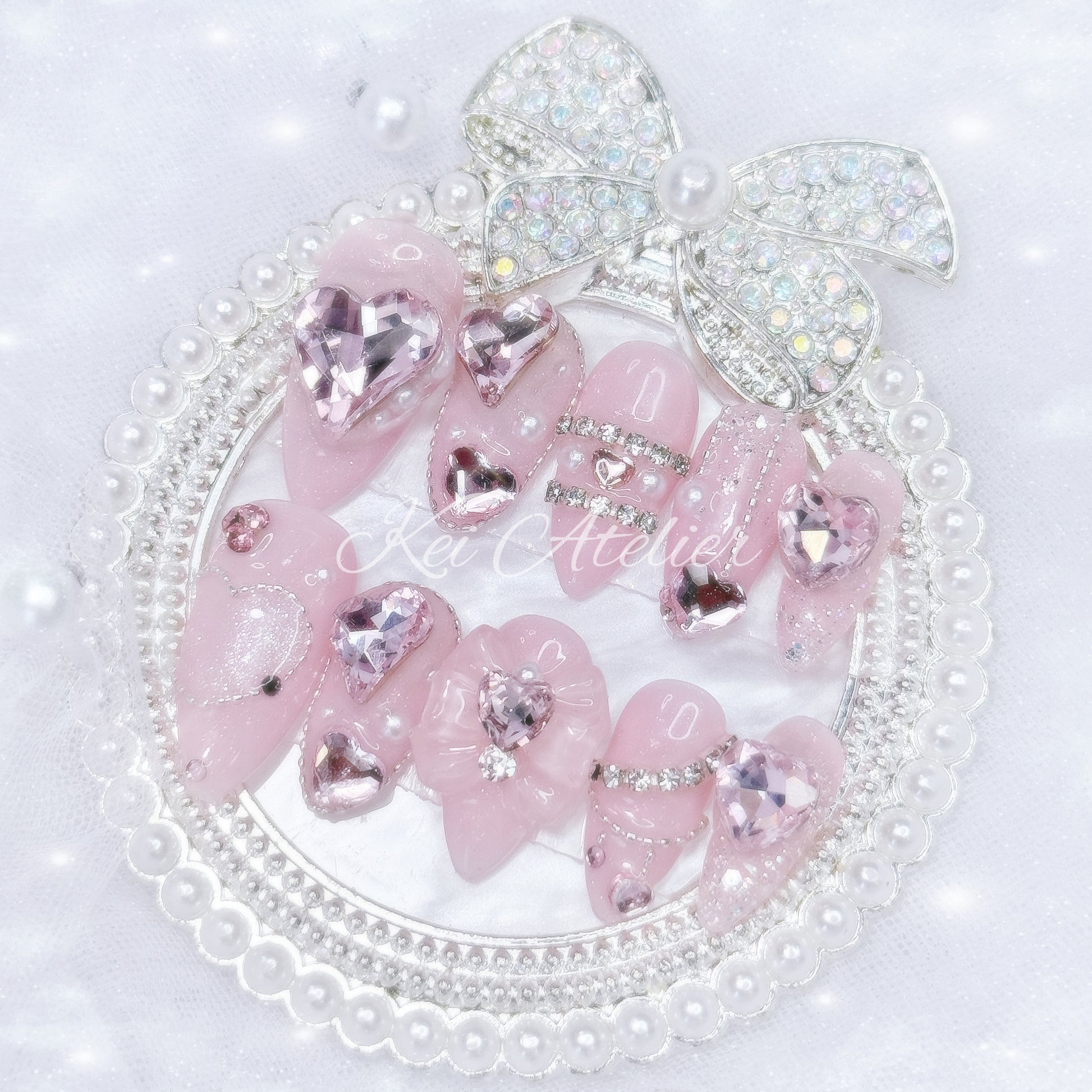 Kawaii Japanese ryousangata jirai style handmade press-on nail set featuring pink sparkly gel, bejeweled in heart crystal rhinestones, pearls, and glitter.