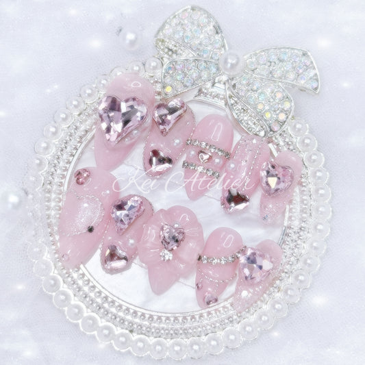 Kawaii Japanese ryousangata jirai style handmade press-on nail set featuring pink sparkly gel, bejeweled in heart crystal rhinestones, pearls, and glitter.