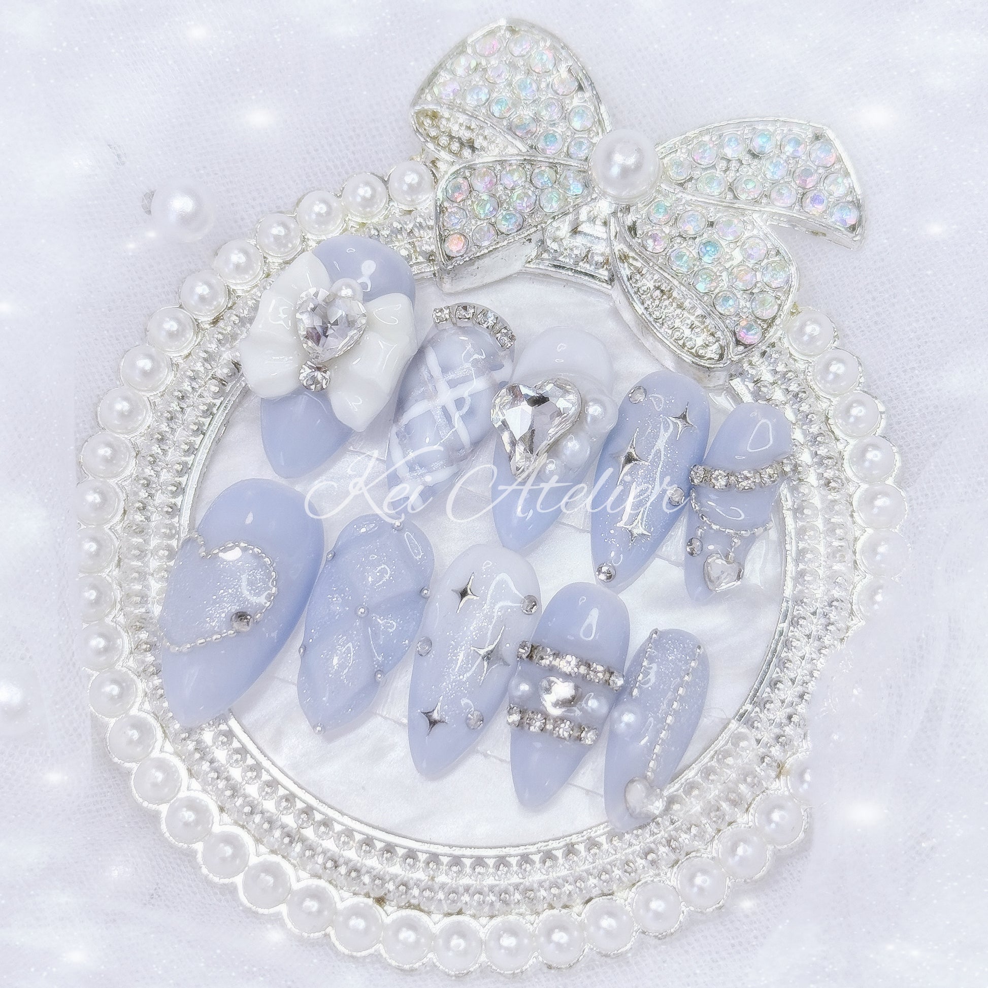 Kawaii Japanese ryousangata jirai style handmade press-on nail set featuring milky blue and white gels, glitter, shimmer, 3d cushion design, silver startlight stickers, pearls, rhinestones, ribbon and bow charms, inspired by moonlight