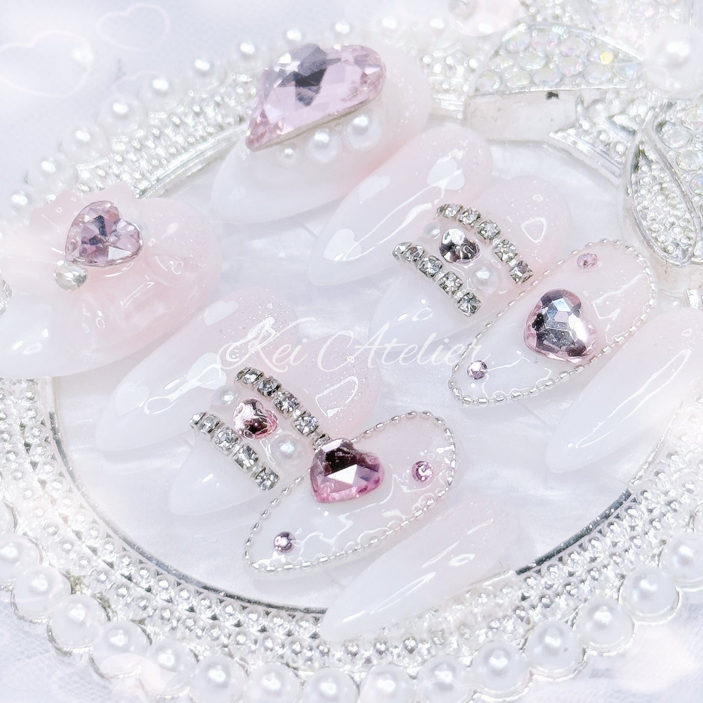 Kawaii Japanese ryousangata jirai style handmade press-on nail set featuring pink and white ombre, sugary sparkles, and bejeweled in pink heart crystals, a ribbon, and white hearts