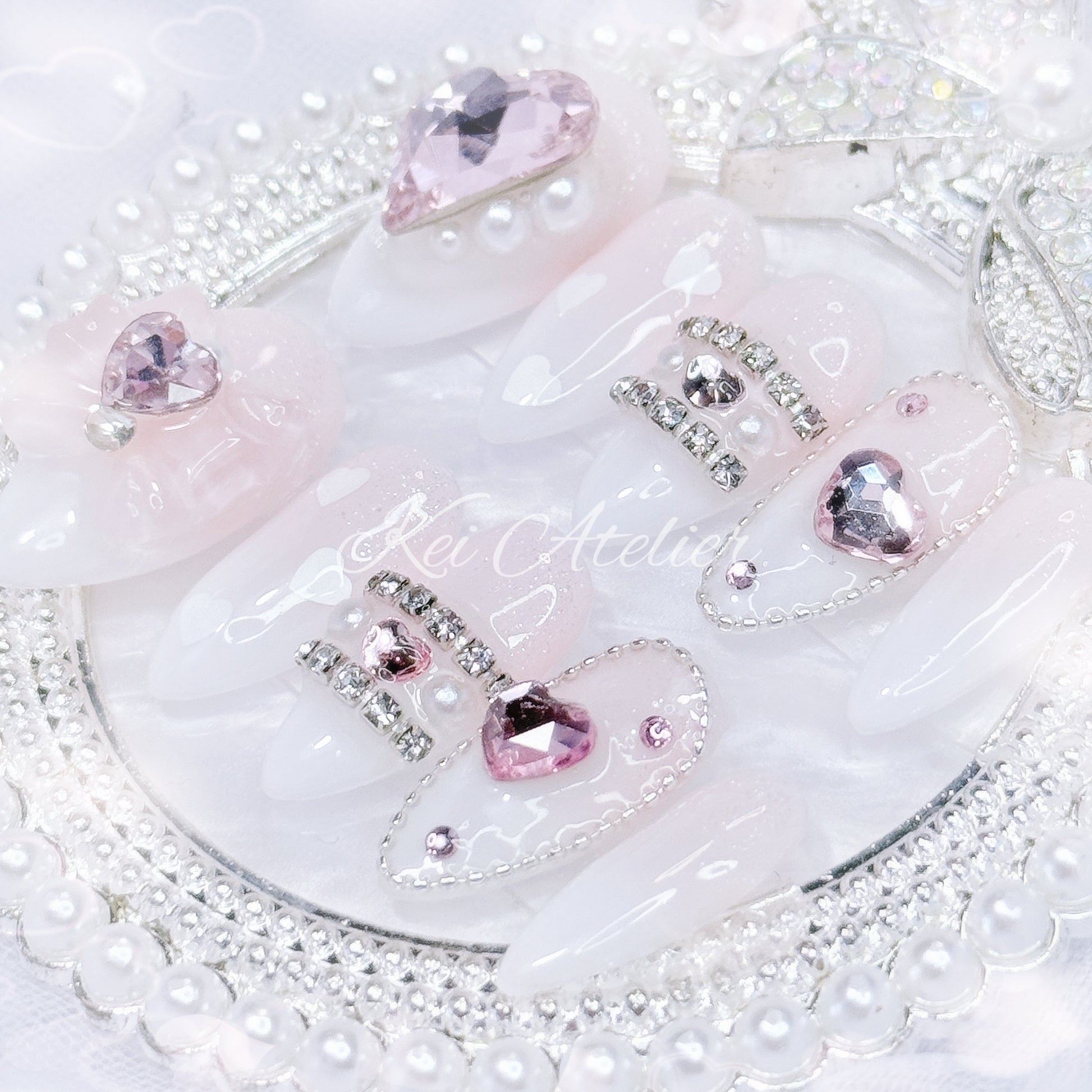 Kawaii Japanese ryousangata jirai style handmade press-on nail set featuring pink and white ombre, sugary sparkles, and bejeweled in pink heart crystals, a ribbon, and white hearts