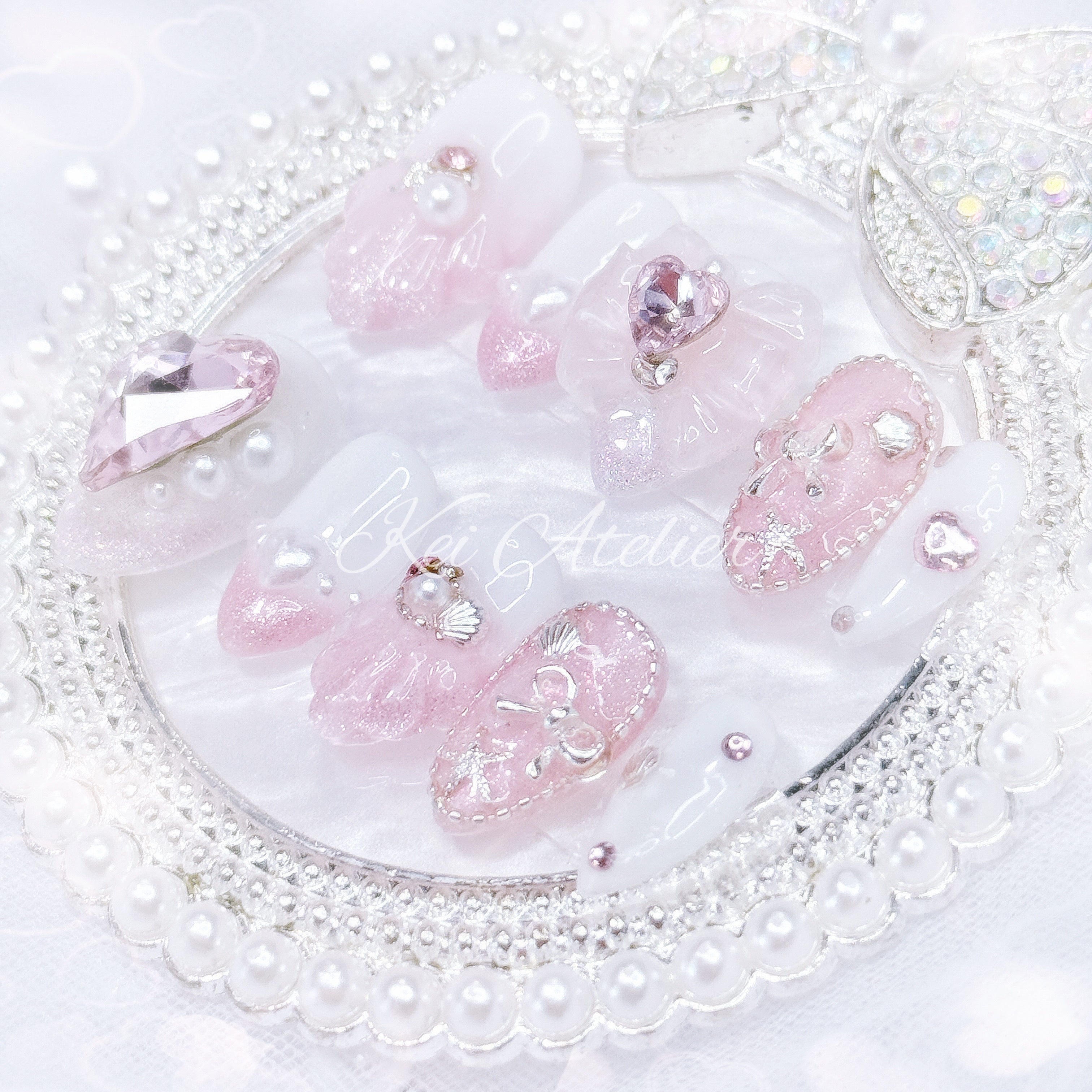Kawaii Japanese ryousangata jirai style handmade press-on nail set featuring pink and white ombre glitter gels, 3d shell design, decorated with pearls, seashells, pink hearts and jewels, rhinestones, and bows