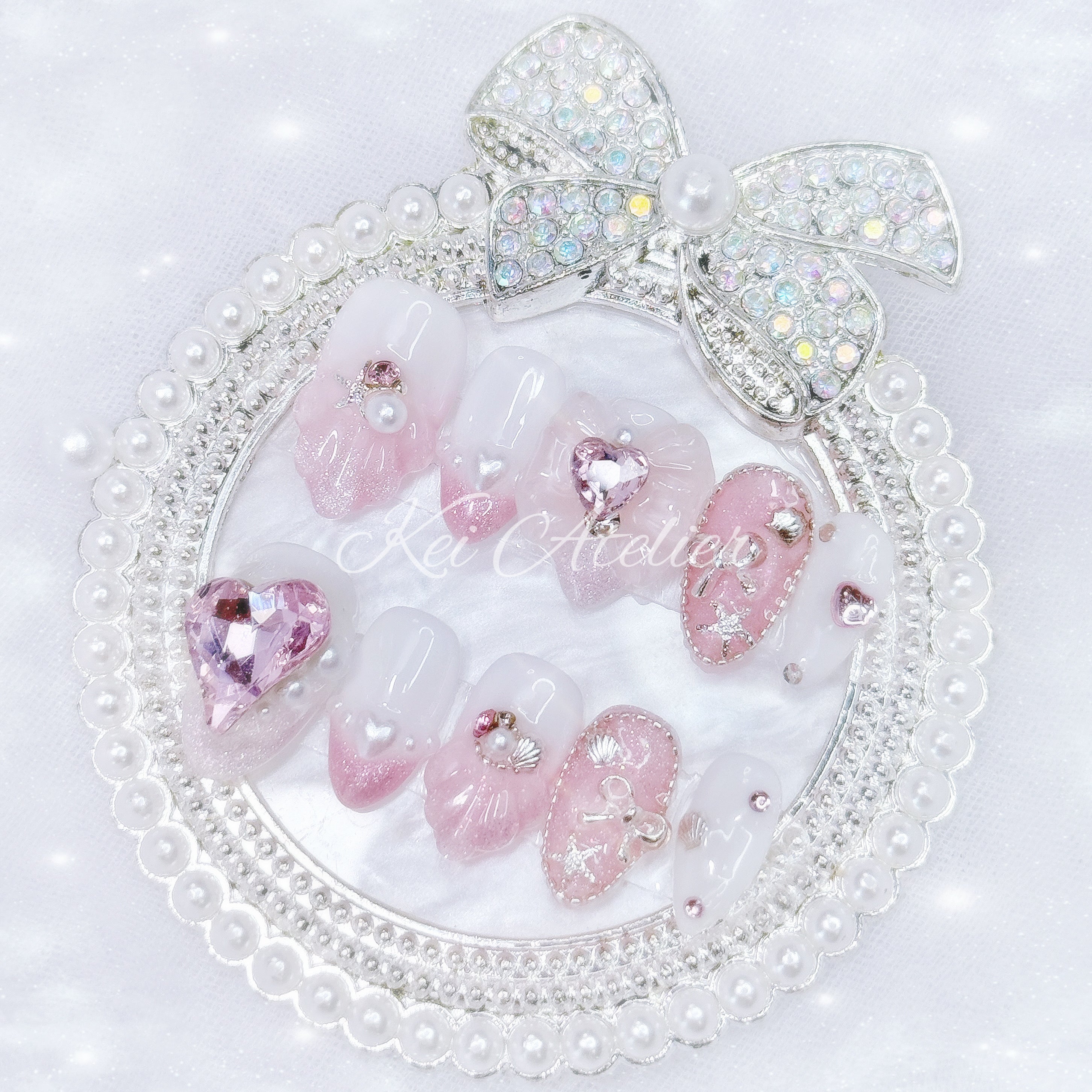 Kawaii Japanese ryousangata jirai style handmade press-on nail set featuring pink and white ombre glitter gels, 3d shell design, decorated with pearls, seashells, pink hearts and jewels, rhinestones, and bows