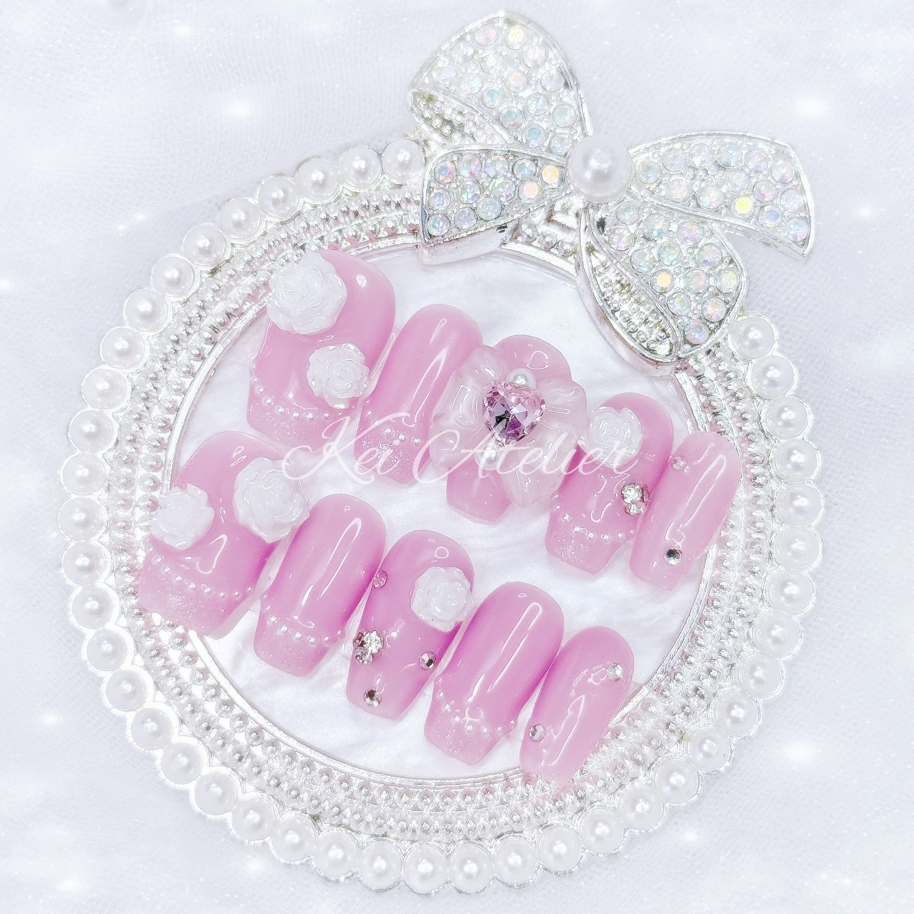 Japanese style handmade press-on nail set featuring jelly pink gels, white pearl glitter french tips, white rose charms, rhinestones, and a white bow with a pink heart ribbon charm