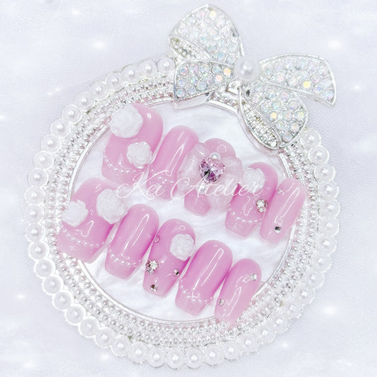 Japanese style handmade press-on nail set featuring jelly pink gels, white pearl glitter french tips, white rose charms, rhinestones, and a white bow with a pink heart ribbon charm
