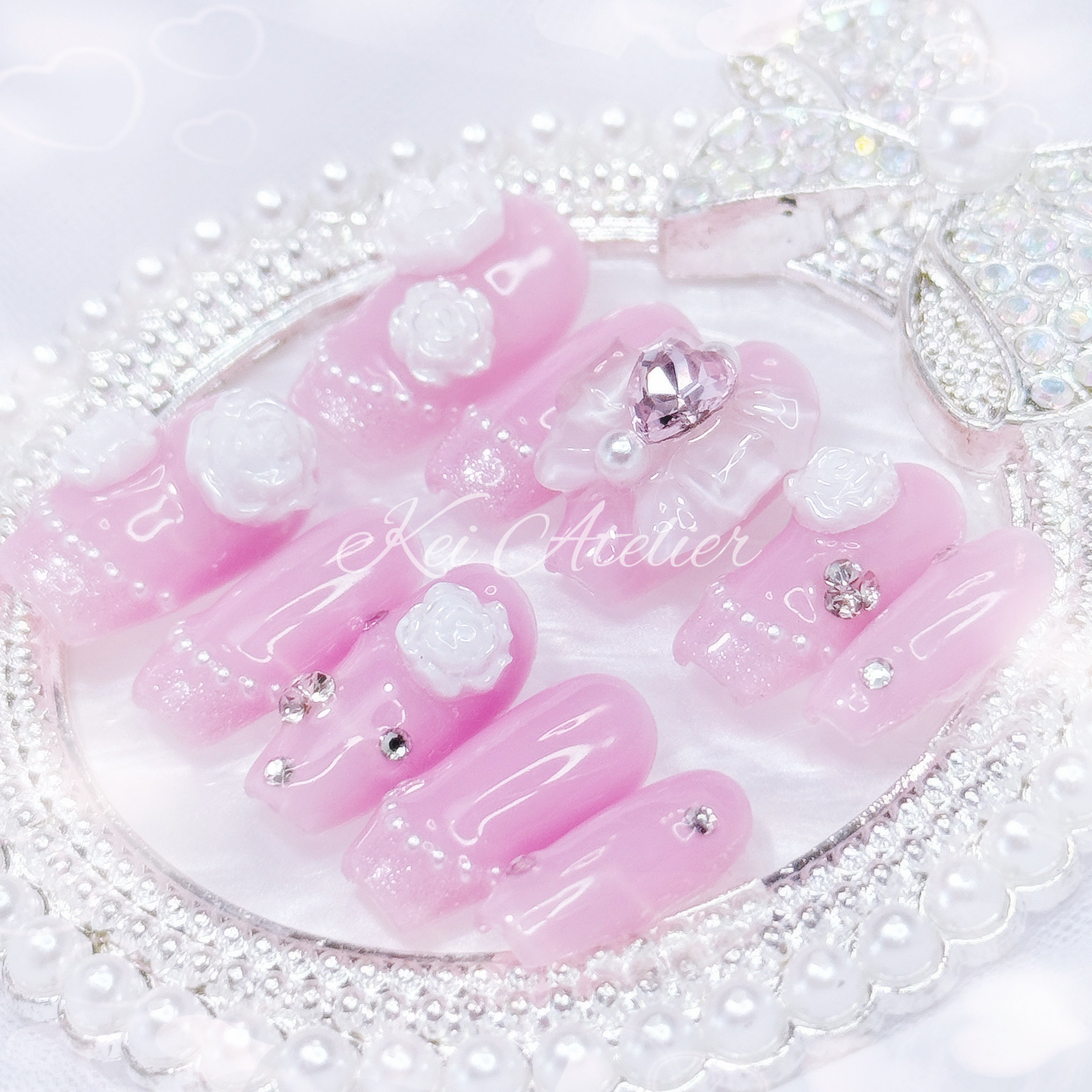 Japanese style handmade press-on nail set featuring jelly pink gels, white pearl glitter french tips, white rose charms, rhinestones, and a white bow with a pink heart ribbon charm