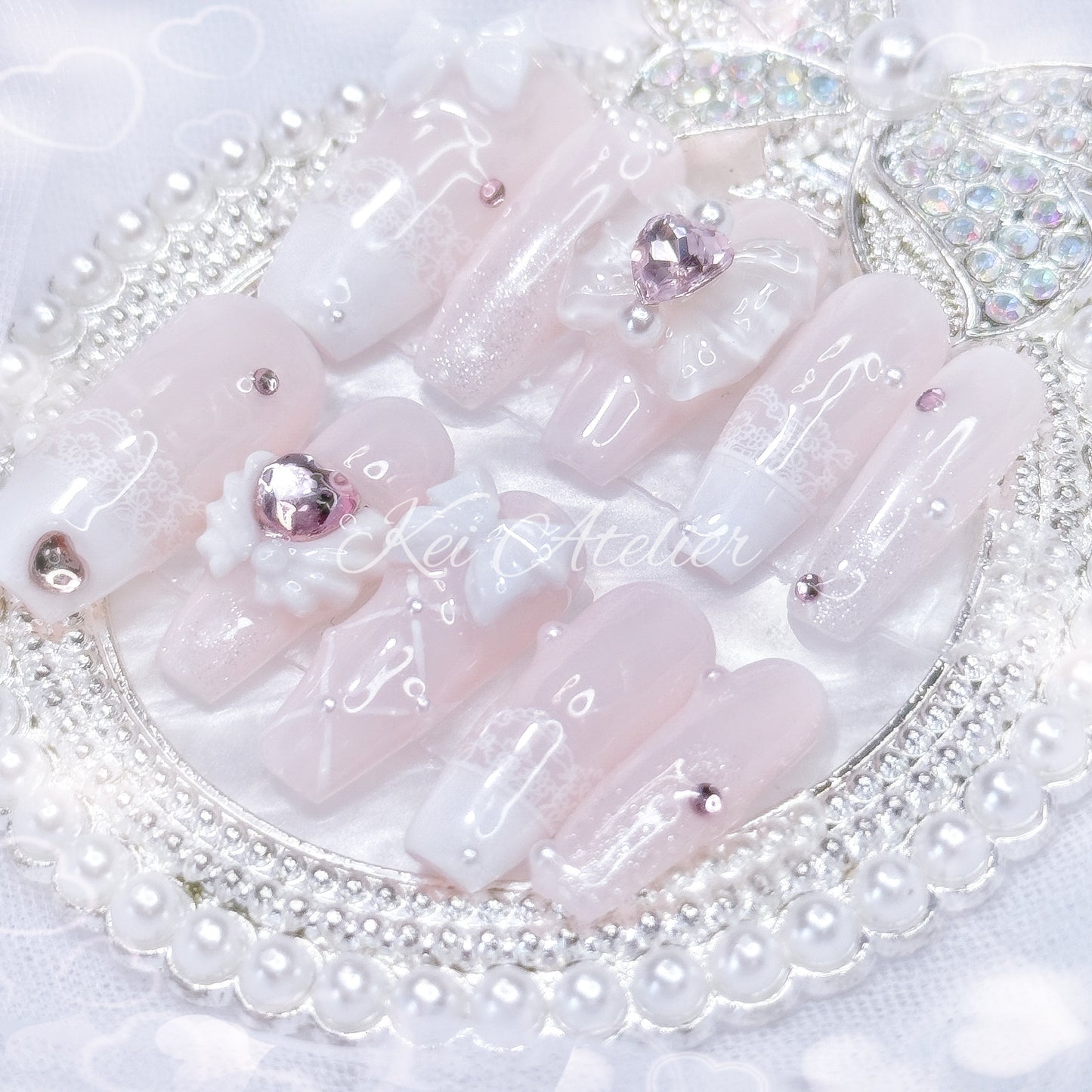 Kawaii Japanese ryousangata jirai style handmade press-on nail set featuring baby pink and white gels, lace french tips, adorned in ribbons, bows, angel wings, hearts, and glitter