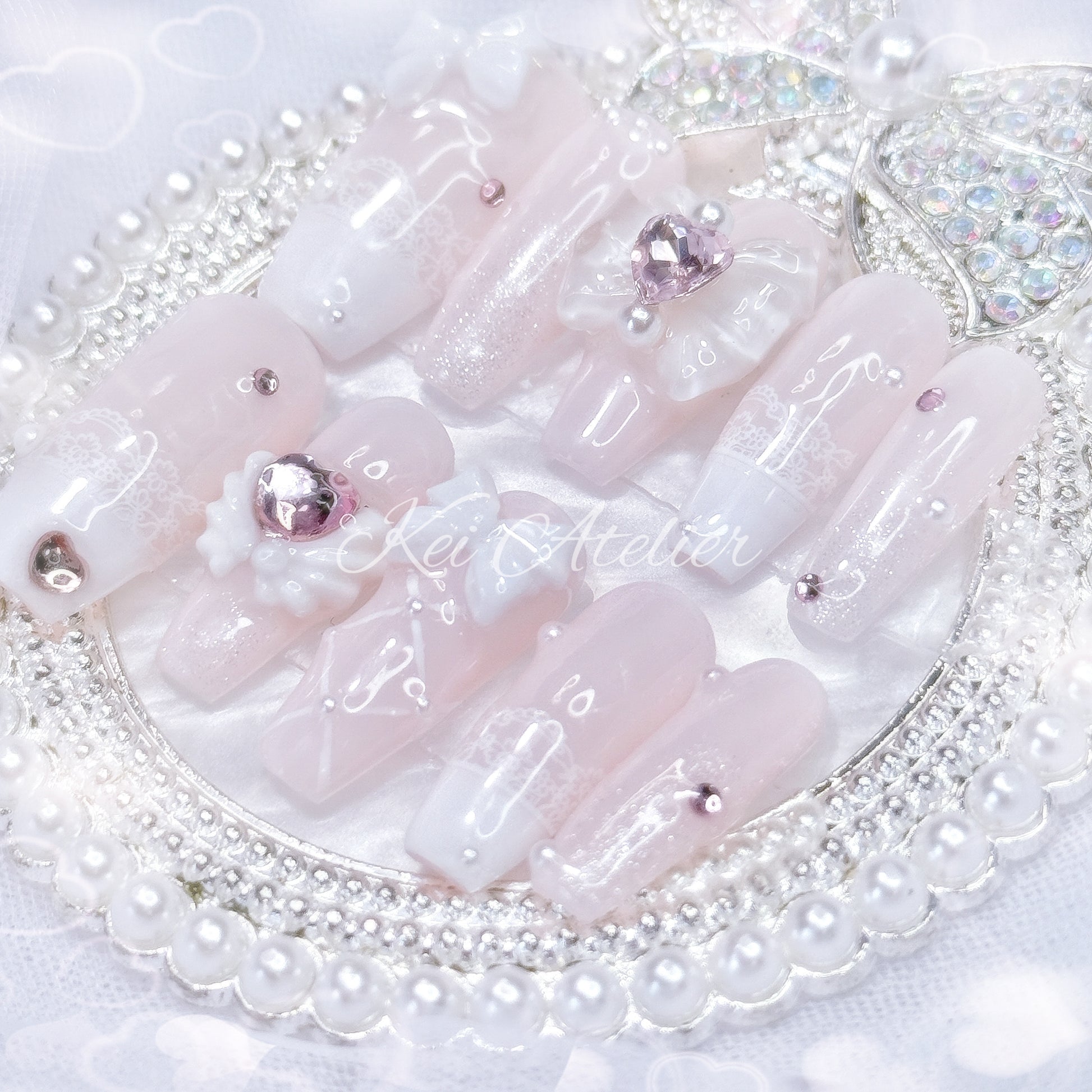 Kawaii Japanese ryousangata jirai style handmade press-on nail set featuring baby pink and white gels, lace french tips, adorned in ribbons, bows, angel wings, hearts, and glitter