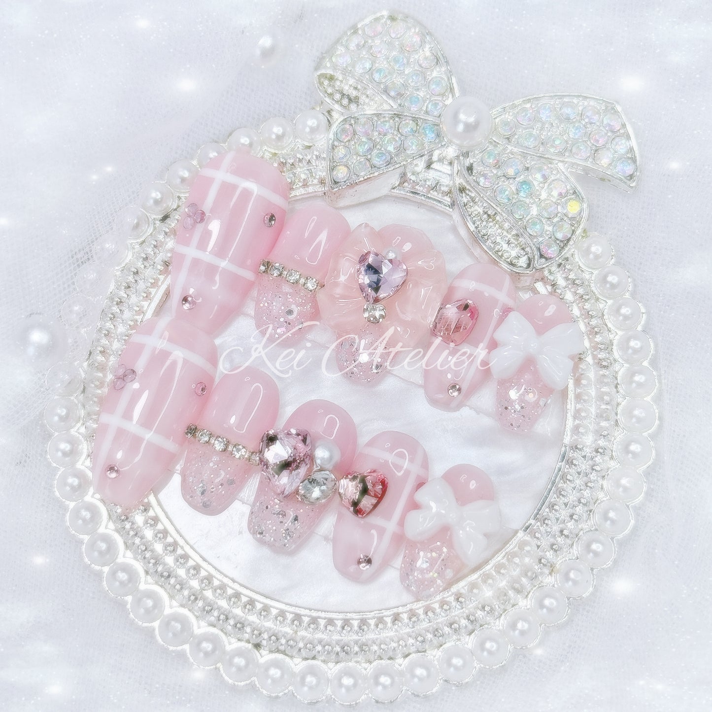 Kawaii Japanese ryousangata jirai style handmade press-on nail set featuring a pink and white plaid design, with pink heart crystals, ribbons, bows, and sparkly silver glitter